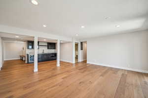 Unfurnished living room with light wood-type flooring, recessed lighting, and beverage cooler