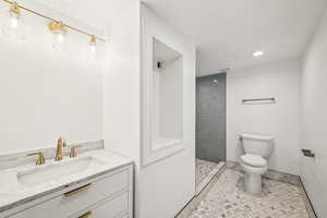 Bathroom with vanity, tile patterned flooring, a tile shower, and recessed lighting