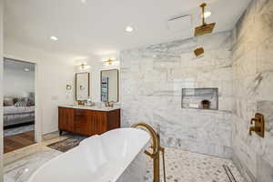 Ensuite bathroom with a freestanding tub, double vanity, recessed lighting, a marble finish shower, and tile walls