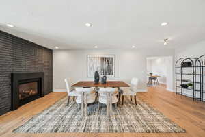 Dining space featuring light wood-style flooring, recessed lighting, a fireplace, and a textured ceiling