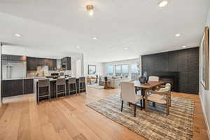 Dining room with a fireplace, light wood-type flooring, and recessed lighting