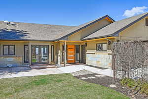 View of exterior entry featuring french doors, roof with shingles, stucco siding, and stone siding