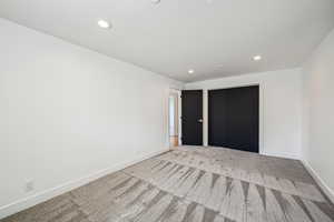 Unfurnished bedroom featuring recessed lighting, carpet flooring, and a closet