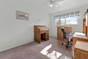 Carpeted home office with baseboards and ceiling fan
