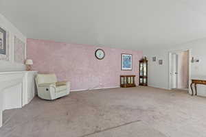 Unfurnished room with carpet floors, a brick fireplace, and wallpapered walls