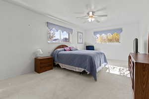 Carpeted bedroom with a ceiling fan and baseboards