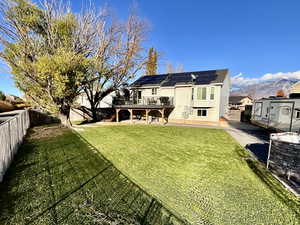 Back of property featuring a fenced backyard, solar panels, a deck with mountain view, and a patio area