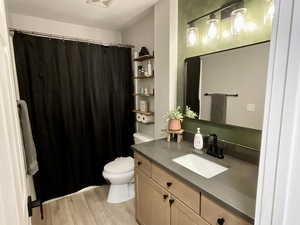 Full bath featuring a shower with new lighting, vanity, and light wood-type flooring