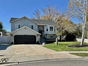 Split foyer home with brick siding, driveway, and a garage