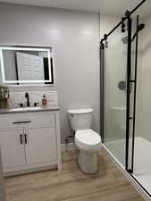 3/4 bathroom with a stall shower, vanity, and light wood-style flooring