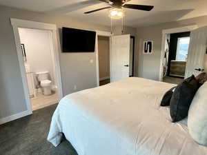 Bedroom featuring ensuite bathroom, a ceiling fan, and dark colored carpet