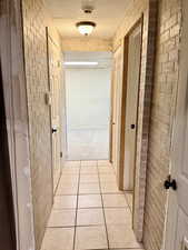 Hall with brick wall and light tile patterned floors