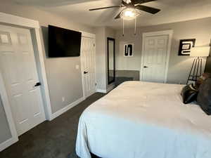 Bedroom with a ceiling fan and dark colored carpet