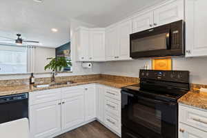 Kitchen featuring black appliances, white cabinetry, light stone counters, dark wood-style floors, and recessed lighting
