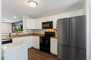 Kitchen featuring black appliances, white cabinets, dark wood-style floors, light stone countertops, and recessed lighting