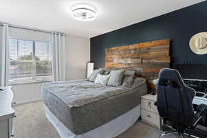 Bedroom featuring carpet floors, a textured ceiling, a desk, and an accent wall