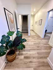 Corridor featuring light wood-style floors, stairs, and recessed lighting
