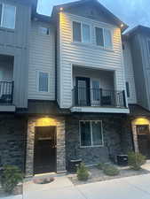 View of front of home featuring a balcony, a standing seam roof, a metal roof, and brick siding