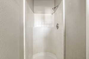 Primary bathroom featuring a textured wall and a stall shower