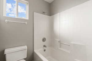Bathroom featuring a textured wall and  shower combination