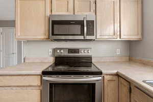 Kitchen with light brown cabinets, stainless steel appliances, and light countertops