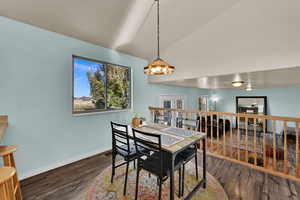 Dining room featuring dark wood-style flooring and vaulted ceiling