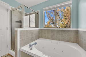 Bathroom featuring a stall shower and a tub with jets