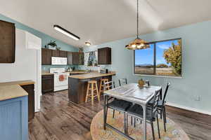 Dining space with vaulted ceiling and dark wood-type flooring