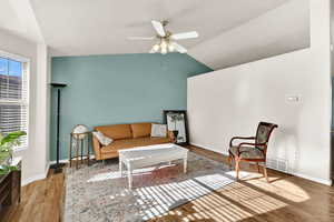 Living area featuring ceiling fan, vaulted ceiling, wood finished floors, and a textured ceiling