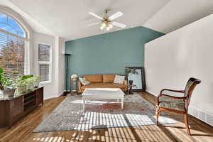 Sitting room with vaulted ceiling, wood finished floors, a ceiling fan, and a textured ceiling