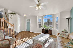 Living room with stairway, wood finished floors, a textured ceiling, and ceiling fan