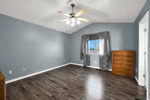 Unfurnished bedroom featuring lofted ceiling, dark wood-style floors, and ceiling fan