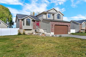View of front of property featuring brick siding, driveway, an attached garage, and stucco siding