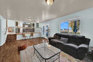 Living area featuring wood finished floors, a textured ceiling, and stairway