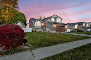 Traditional home with brick siding, a garage, concrete driveway, and stucco siding