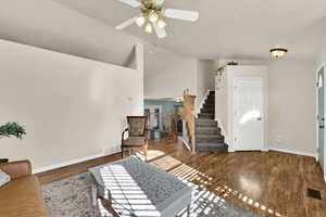 Living area featuring vaulted ceiling, wood finished floors, stairs, and ceiling fan