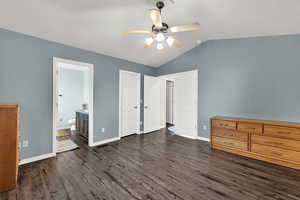 Unfurnished bedroom featuring lofted ceiling, dark wood-style flooring, a ceiling fan, and ensuite bathroom