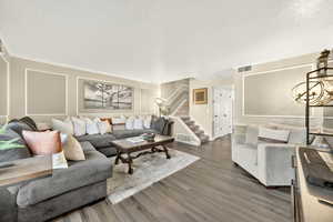 Living room featuring wood finished floors, stairs, a chandelier, and a textured ceiling
