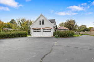 View of home's exterior featuring a garage, asphalt driveway, stucco siding, and a standing seam roof