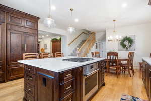 Kitchen featuring dark brown cabinets, decorative light fixtures, appliances with stainless steel finishes, light wood-type flooring, and recessed lighting