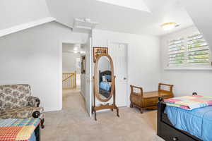 Bedroom featuring attic access, light colored carpet, multiple windows, and a textured ceiling