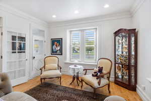 Sitting room with crown molding, healthy amount of natural light, light wood-type flooring, and recessed lighting