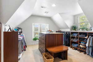 Spacious closet featuring light colored carpet and lofted ceiling