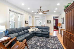 Living room with ornamental molding, light wood-type flooring, a ceiling fan, and recessed lighting