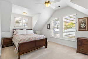 Bedroom featuring carpet flooring, multiple windows, vaulted ceiling, and ceiling fan