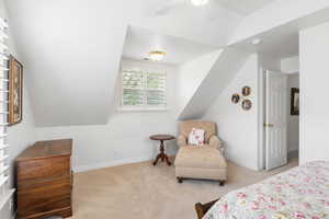 Carpeted bedroom with a ceiling fan and vaulted ceiling