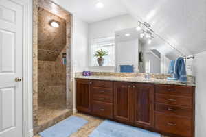 Bathroom with vanity, walk in shower, vaulted ceiling, and a textured ceiling