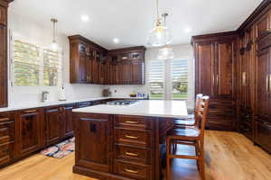 Kitchen featuring a center island, light wood-style flooring, hanging light fixtures, dark brown cabinets, and recessed lighting