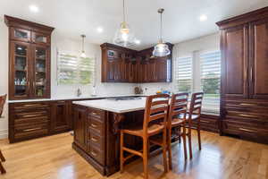 Kitchen featuring hanging light fixtures, a center island, dark brown cabinetry, a kitchen bar, and light wood finished floors
