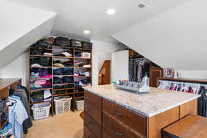 Spacious closet with light colored carpet and vaulted ceiling
